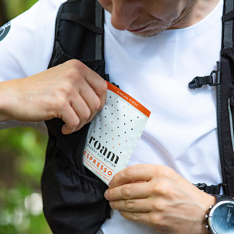 Male Trail Runner Putting Roam Energy Nut Butter Packet into running vest | Roam | NZ Australia