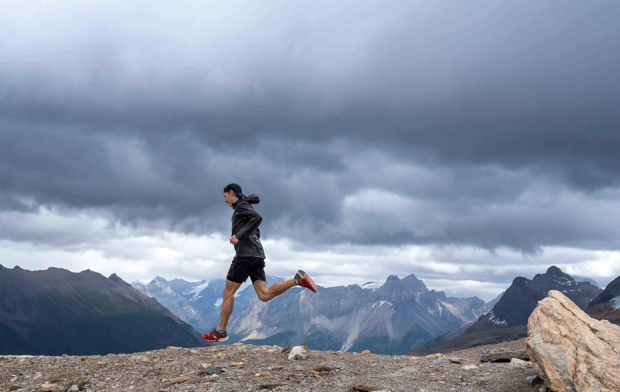 Male trail runner on rocky trails with mountain ranges in background | Roam | NZ Australia